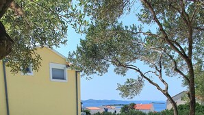 A pool area with lounge chairs and a table, surrounded by greenery and a view of the sea. - Holiday Home in Drage with Seaview, Balcony, Air condition, WIFI (571-1) (Drage)