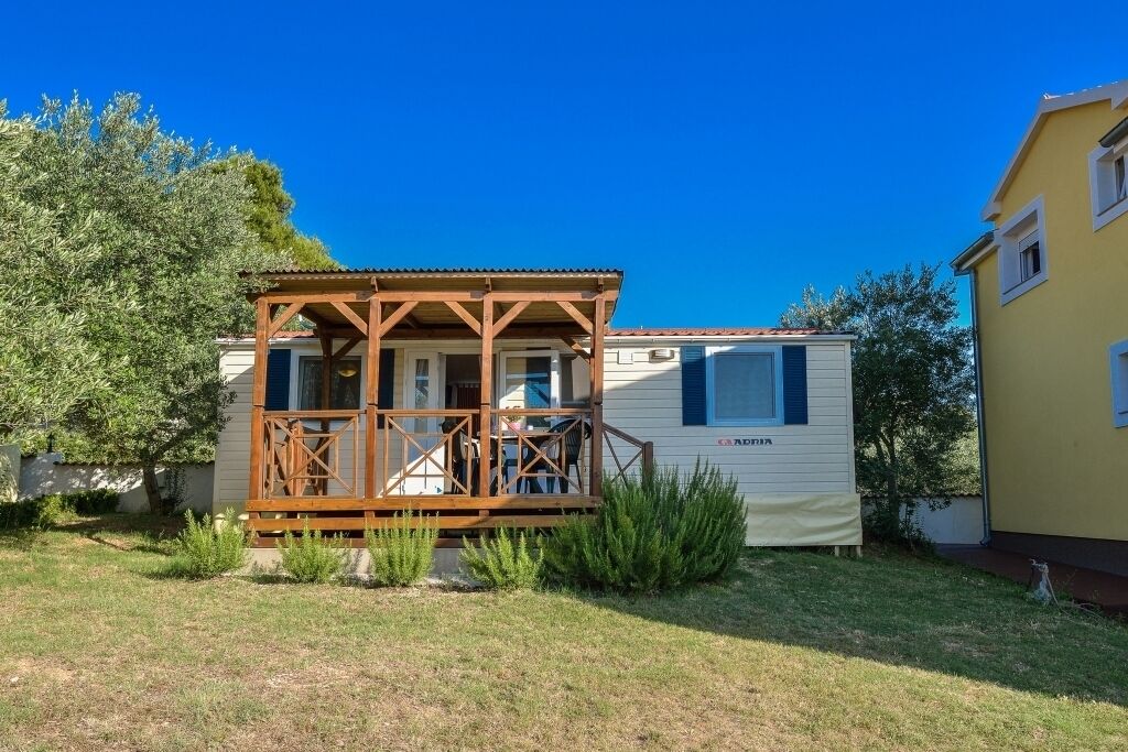 A mobile home with a wooden porch, a small deck, and a white exterior.