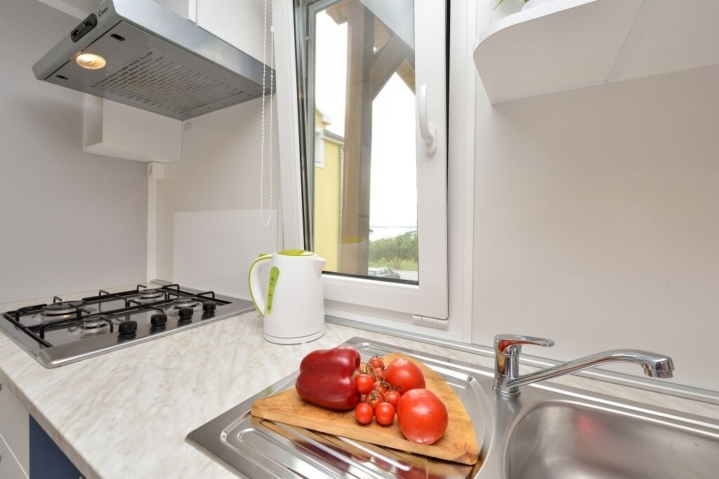 Une cuisine équipée d’une cuisinière à gaz, d’un évier et d’une fenêtre.