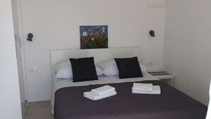 A bedroom with a bed, pillows, a painting on the wall, and a nightstand. - Studio apartment in Podgora with Seaview, Balcony, Air condition, WIFI (4492-4) (Podgora)