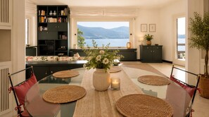 Un coin repas avec une table en verre, des sets de table en fibres tressées et un vase rempli de fleurs.
