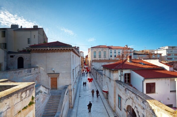 A narrow street with buildings on both sides, a staircase on the left, and a red ribbon hanging across the street. - Apartment in Bibinje with Seaview, Balcony, Air condition, WIFI (59-2) (Bibinje)
