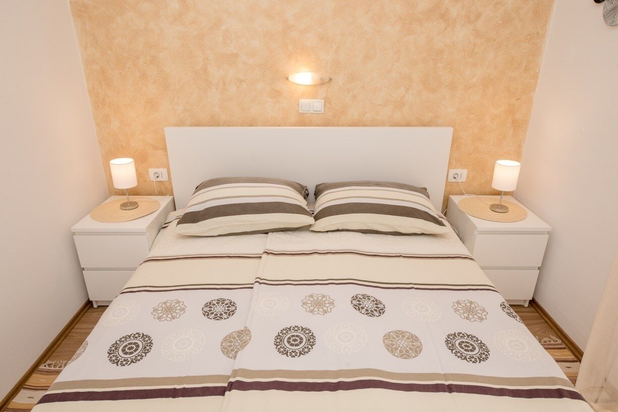 Un lit bien fait, avec une couvre-lit à rayures et deux lampes de chevet.
