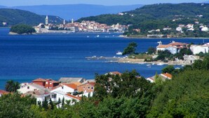 A coastal town with buildings along the waterfront, a prominent church, and a small island with a tower. - Apartment in Barbat with Seaview, Balcony, Air condition, WIFI (3664-3) (Rab)