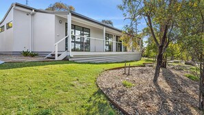 A modern two-story house with a flat roof, large windows, and a covered porch.