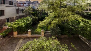 A courtyard with stone steps, lush greenery, and buildings with traditional architecture. - Ca' Mainella Grand Canal (Venice)