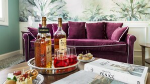 A dining table with a tray of appetizers, two bottles of Bacardi, two glasses of red wine, and a book titled "Magical Venice". - Ca' Mainella Grand Canal (Venice)