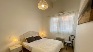 Une chambre à coucher avec un lit, deux lampes de chevet, une chaise, un radiateur et une fenêtre avec des rideaux.