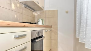 Een keuken met een gasfornuis, oven en waterkoker op het aanrecht.