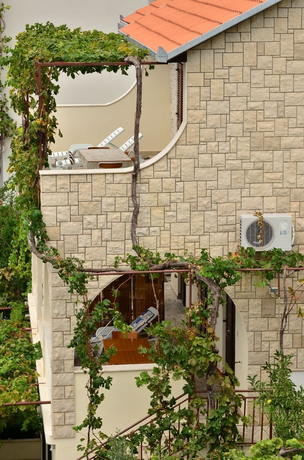A multi-level building with stone walls, a rooftop terrace, and a covered outdoor seating area.