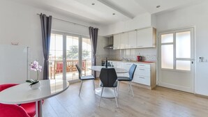 Una cucina moderna con mobili bianchi, un tavolo da pranzo rotondo e una sedia rossa.