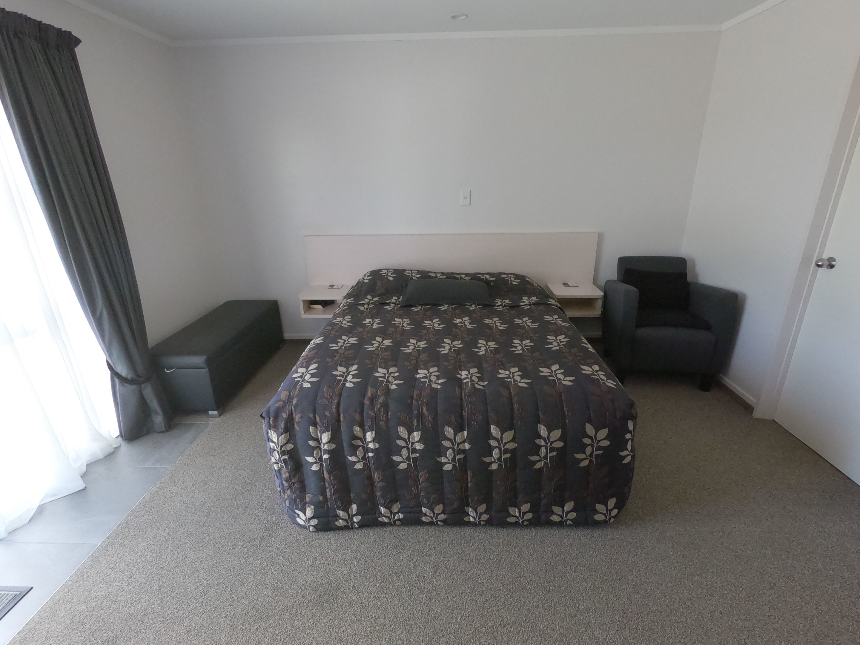 A bedroom with a bed, bedside tables, a chair, and a bench.