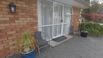 A house with a brick exterior, a sliding glass door, a potted plant, and a chair outside.