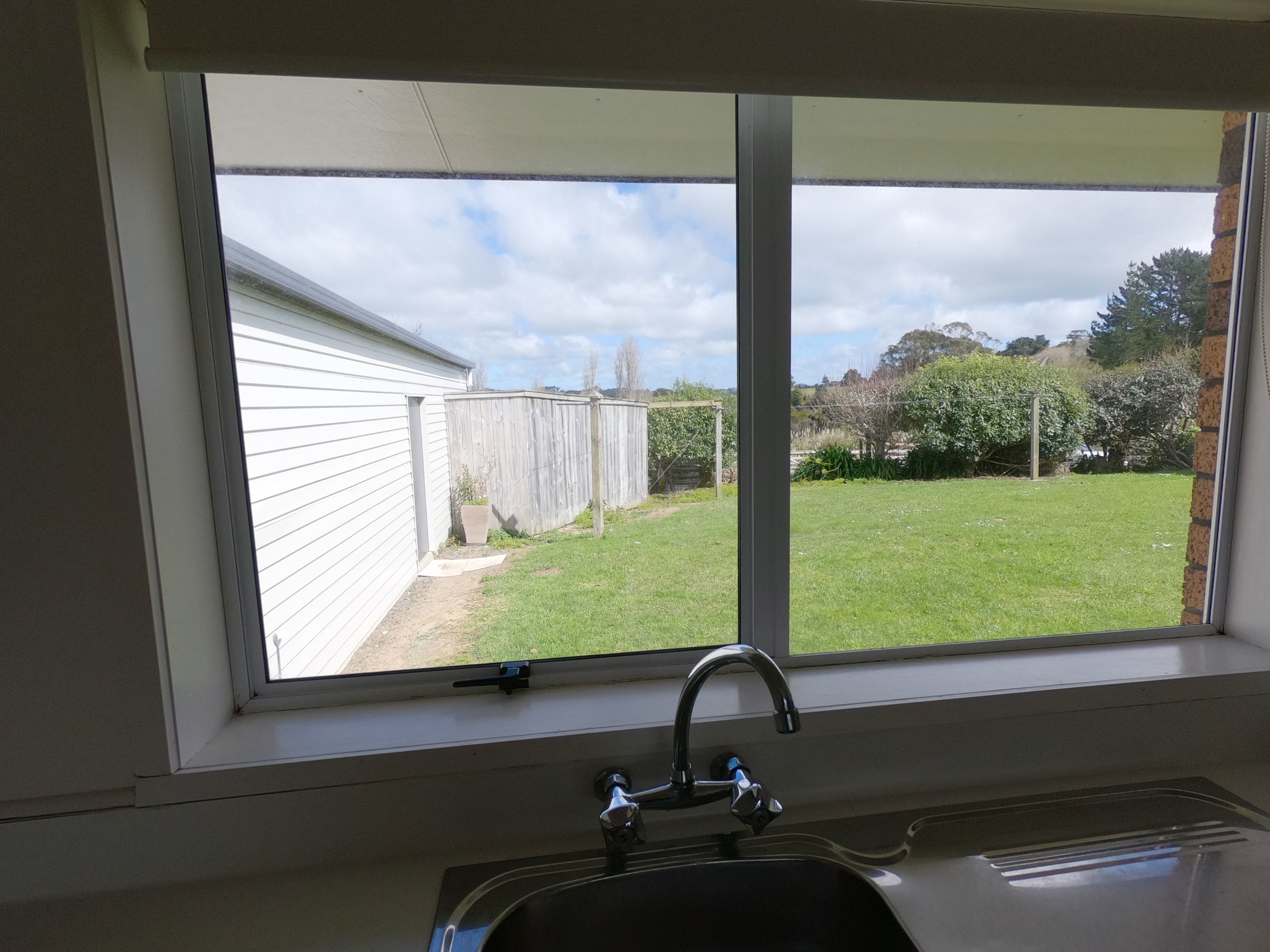 A kitchen with a window overlooking a backyard.