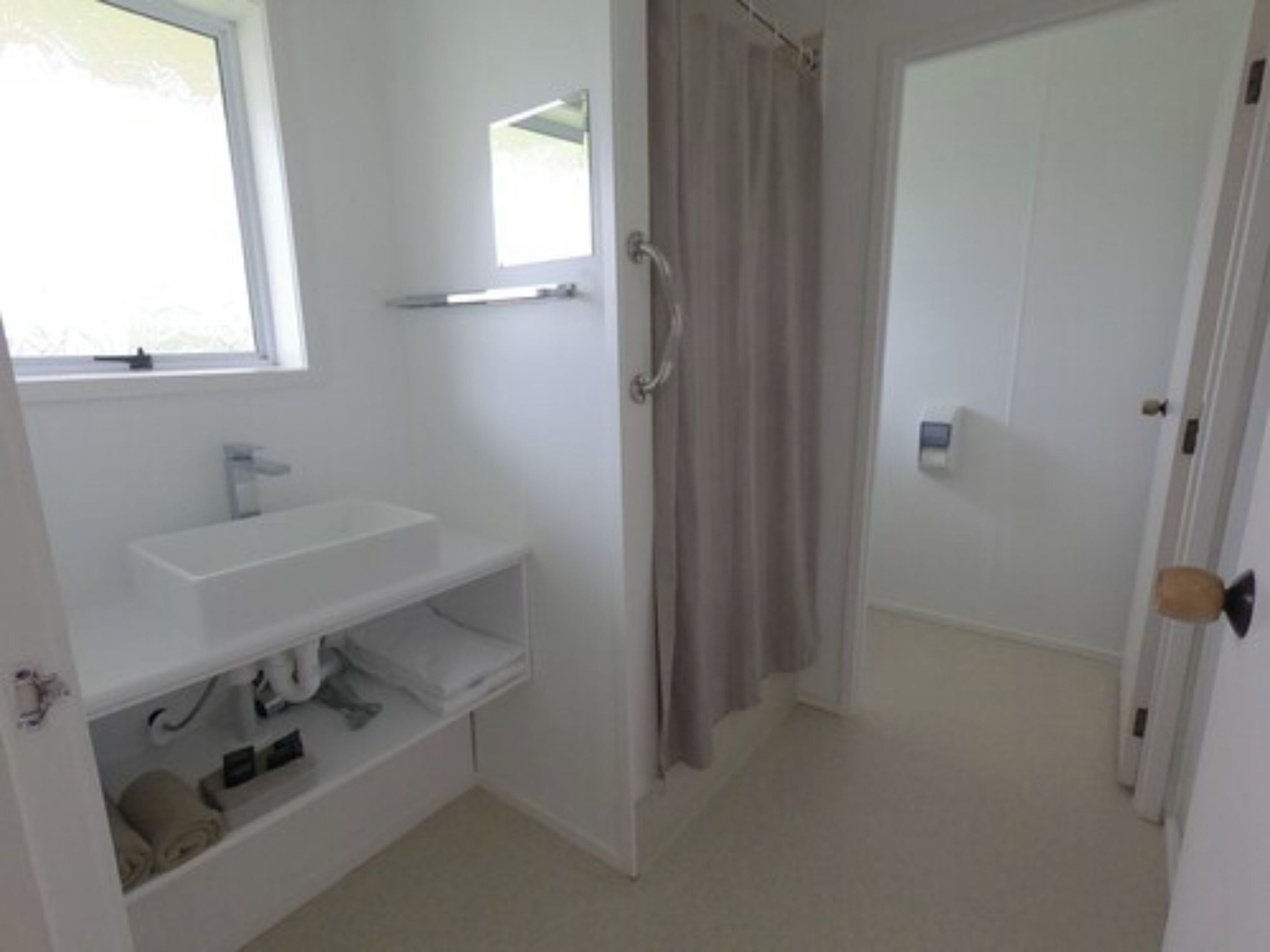 A bathroom with a white sink, mirror, and shower curtain.