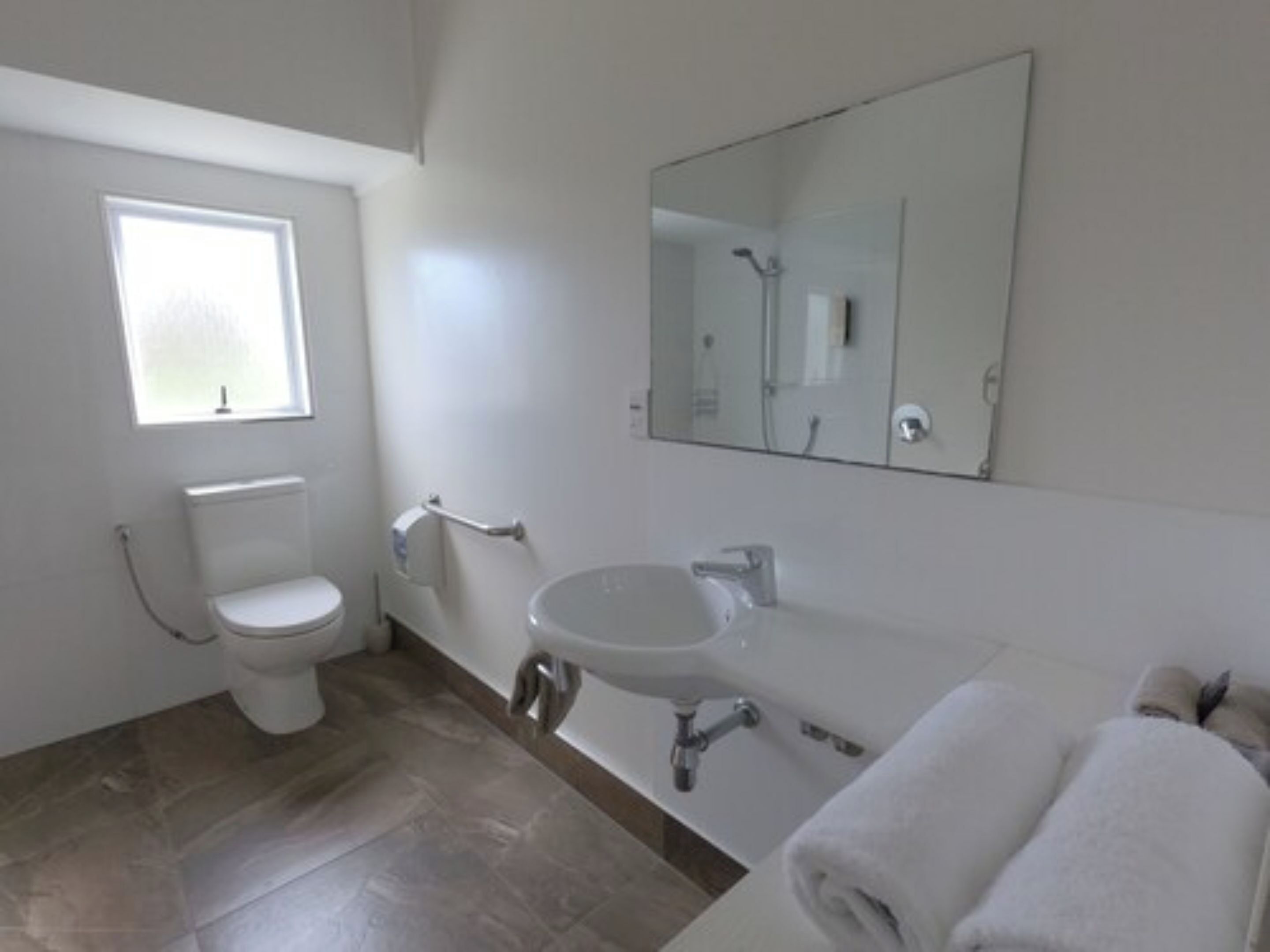 Un baño moderno con inodoro, lavamanos y un espejo grande.