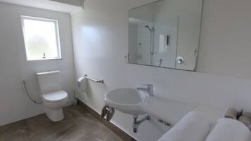 Un baño moderno con inodoro, lavamanos y un espejo grande.