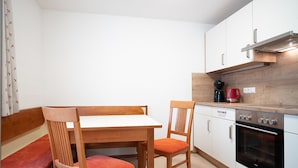 Een gezellige, kleine keuken met een houten tafel, twee stoelen, een kookplaat en een koffiezetapparaat.