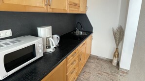A kitchen with wooden cabinets, a black countertop, a microwave, a coffee maker, and a sink. - Apartment in Crikvenica with Seaview, Balcony, Air condition, WIFI (3492-7) (Crikvenica)