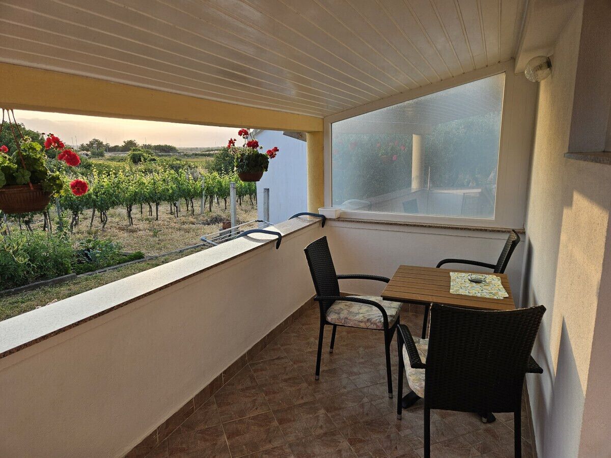 A balcony with a table and chairs, overlooking a vineyard.