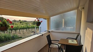 Un balcon avec une table et des chaises, donnant sur un vignoble.