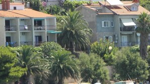 A coastal residential area with multi-story buildings, some with balconies, and a beach with boats and people. - Apartment in Stanići with Seaview, Terrace, Air condition, WIFI (3782-4) (Stanici)