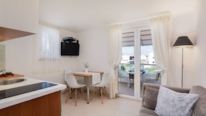 A compact living space with a kitchenette, a dining area with two chairs, a sofa, and a balcony with a table and chairs. - Apartment in Vodice with Seaview, Balcony, Air condition, WIFI (94-10) (Vodice)