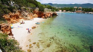 Una playa costera con aguas cristalinas, acantilados rocosos y algunas personas disfrutando.