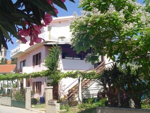 A two-story house with a balcony, surrounded by greenery and a fence. - Apartment in Pakoštane with Terrace, WIFI (3539-3) (Pakoštane)