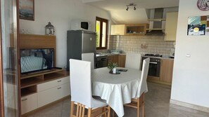 A compact kitchen with a dining area, a refrigerator, a microwave, and a television. - Apartment in Lumbarda with Seaview, Terrace, Air condition, WIFI (128-1) (Lumbarda)