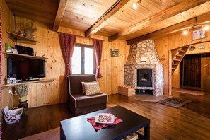 Cozy interior with a stone fireplace, comfortable sofa, and flat-screen TV.