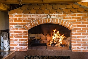 Cozy warmth emanates from this traditional fireplace, complete with a crackling fire and a wooden beam ceiling.