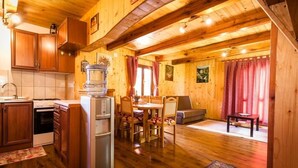 A wooden cabin interior with a kitchen, dining area, and living space.