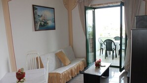 A room with a white sofa, a small table with a vase, a painting on the wall, and a view through a glass door to an outdoor area with chairs. - Apartment in Kali with Seaview, Balcony, Air condition, WIFI (4566-5) (Kali)