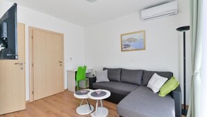 A modern living room with a grey sofa, a small round table, a green chair, and a painting on the wall. - Apartment in Vir with Terrace, Air condition, WIFI, Dishwasher (4589-1) (Vir)