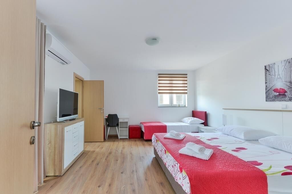 Una habitación pequeña con cama, escritorio, silla y televisión.