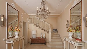 Ein prachtvoller Eingangsbereich mit Treppe, Kronleuchtern und dekorativen Vasen.