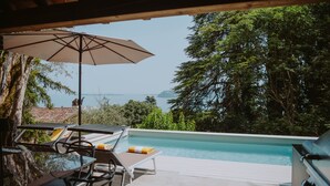 Ein Poolbereich mit Liegestühlen, Sonnenschirm und Grill.