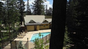 Una casa con piscina, rodeada de árboles y una zona vallada.