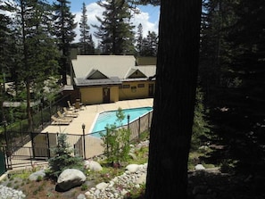 Une maison avec une piscine, entourée d’arbres et disposant d’un espace clôturé.