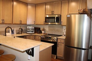 A kitchen with wooden cabinets, a stainless steel refrigerator, a microwave, a stove, and a built-in oven. - Courchevel 37 in Mammoth Lakes, CA (Mammoth Lakes)