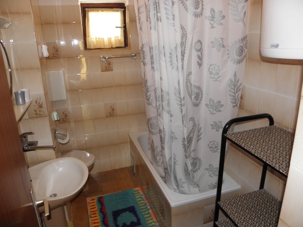 A bathroom with a bathtub, a sink, a shower curtain, and a small window.