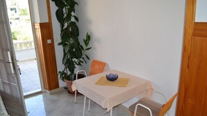 Un pequeño comedor con una mesa y sillas, una planta en maceta y vistas al exterior.