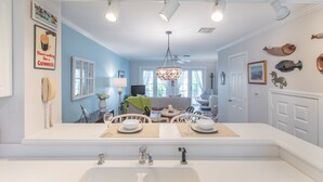 A modern kitchen with a large white sink, a chandelier, and a dining area with a table and chairs. - BELLA VITA ~ 2/1.5 located in the Truman Annex with a community pool! (Key West)