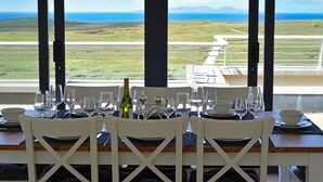 A dining table set for four with a view of the ocean and hills. - Property 260 - Moyard - sleeps 8 guests  in 4 bedrooms (Connemara)