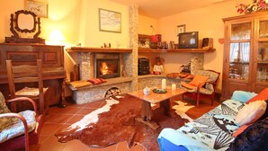Uma sala de estar aconchegante com lareira de pedra, móveis de madeira e tapete de couro.