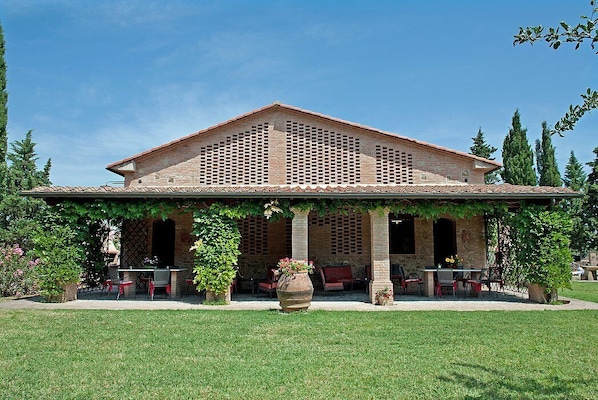 A building with a covered patio area, outdoor seating, and a large planter in the center.
