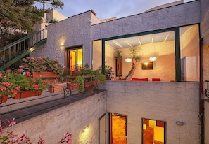 Un bâtiment moderne doté d’un balcon, de plantes en pot et d’un escalier.