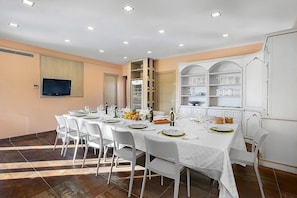 A conference room with a long table set for a meeting, equipped with chairs, a flat-screen TV, and a whiteboard. - Villa Carminia Grande: A splendid and luminous three-story villa located on the coast in front of the island of Capri, with Free WI-FI. (Massa Lubrense)