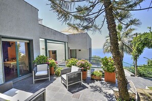 A modern outdoor patio with seating, potted plants, and a view of the sea. - Villa Carminia Grande: A splendid and luminous three-story villa located on the coast in front of the island of Capri, with Free WI-FI. (Massa Lubrense)